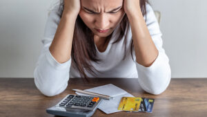 Mujer preocupada revisando sus finanzas personales junto a tarjetas de crédito y documentos.
