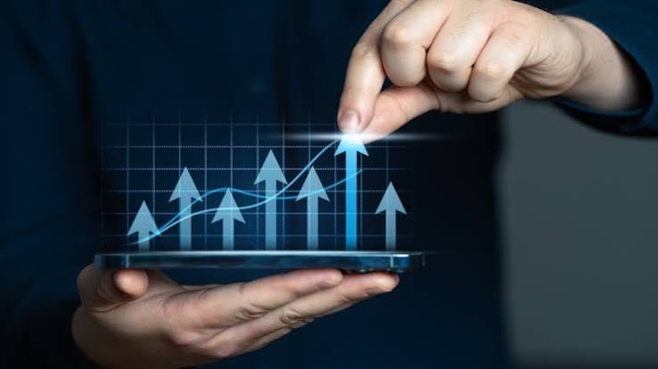 Persona utilizando un dispositivo móvil para representar el crecimiento y progreso financiero. 

