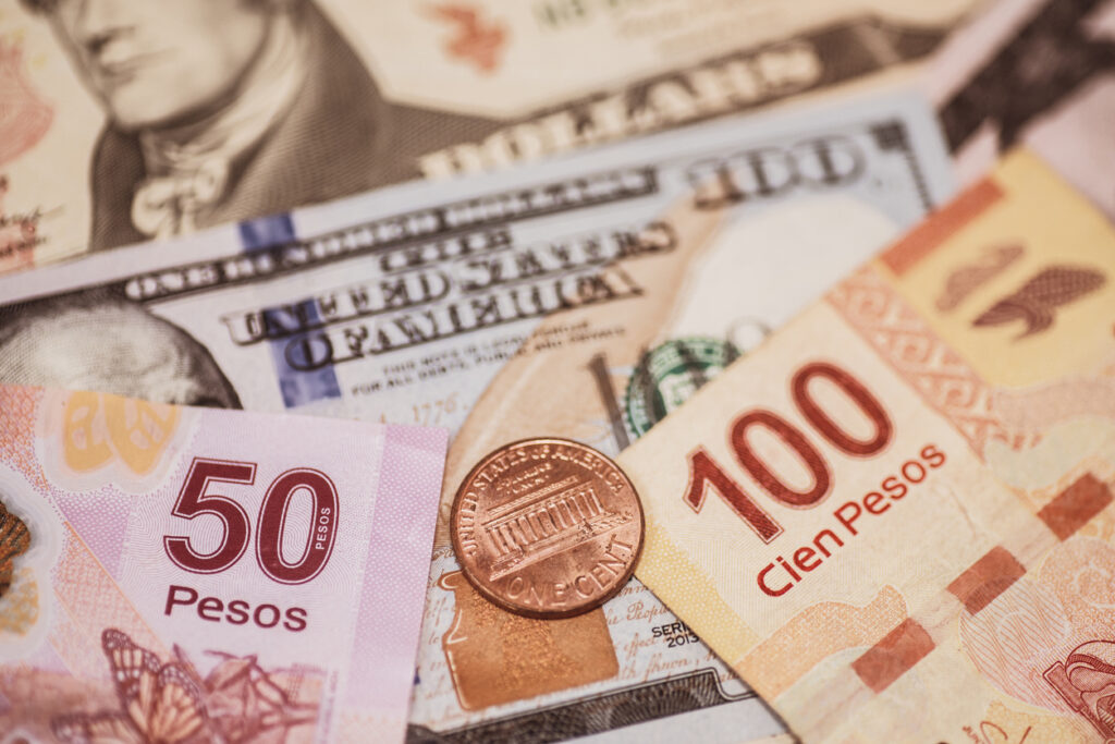 Billetes de pesos mexicanos y dólares estadounidenses junto a una moneda de centavo de dólar, representando la relación entre ambas divisas. 